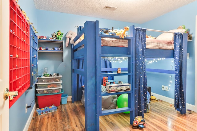 bedroom with a textured ceiling and wood-type flooring