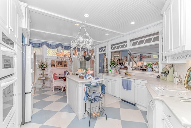 kitchen featuring a notable chandelier, white appliances, white cabinetry, and sink