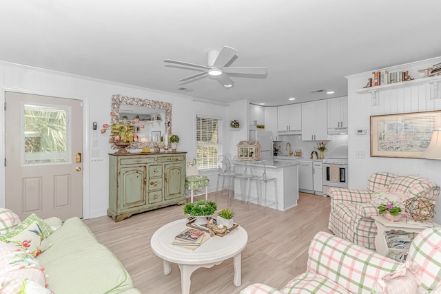 living room featuring ornamental molding, a healthy amount of sunlight, ceiling fan, and light hardwood / wood-style floors