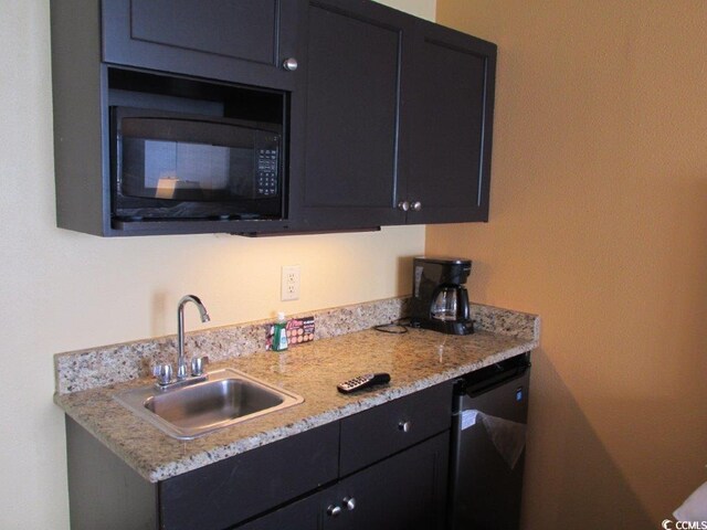 kitchen featuring stainless steel dishwasher, sink, and light stone counters