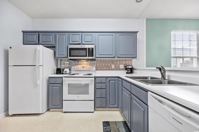 kitchen featuring white appliances, light countertops, gray cabinets, and a sink