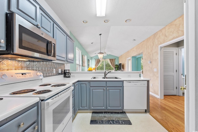 kitchen with blue cabinets, a sink, white appliances, light countertops, and vaulted ceiling