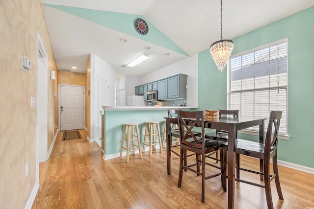 dining room featuring vaulted ceiling, light wood-style floors, baseboards, and a chandelier