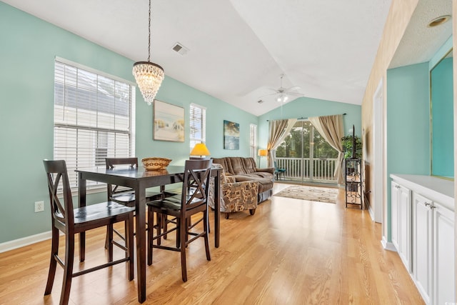 dining space featuring light wood finished floors, visible vents, baseboards, lofted ceiling, and ceiling fan with notable chandelier