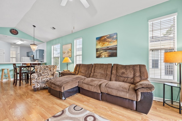 living area featuring a wealth of natural light, visible vents, lofted ceiling, and wood finished floors