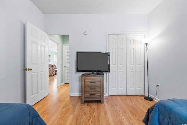 bedroom with baseboards, light wood-type flooring, and a closet