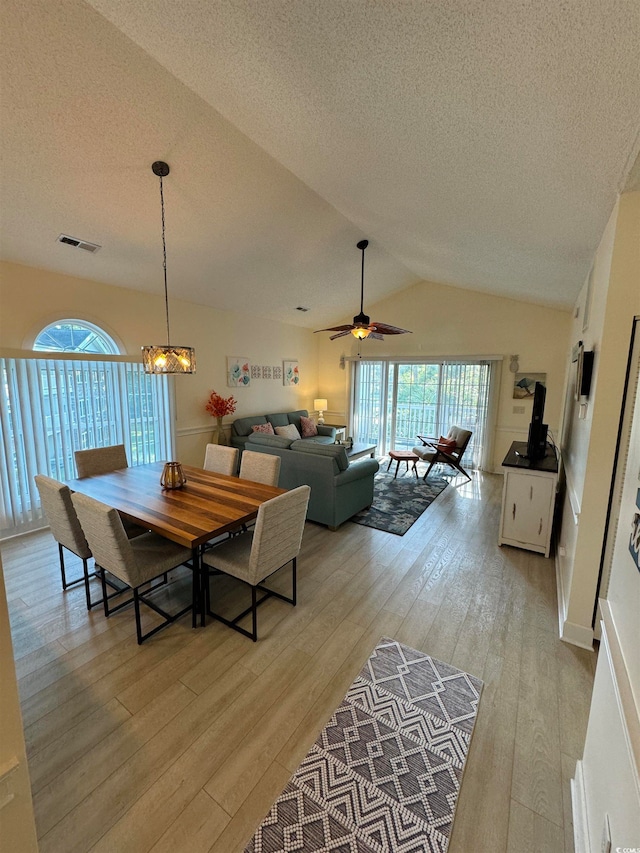 dining room with lofted ceiling, light hardwood / wood-style flooring, a textured ceiling, and ceiling fan