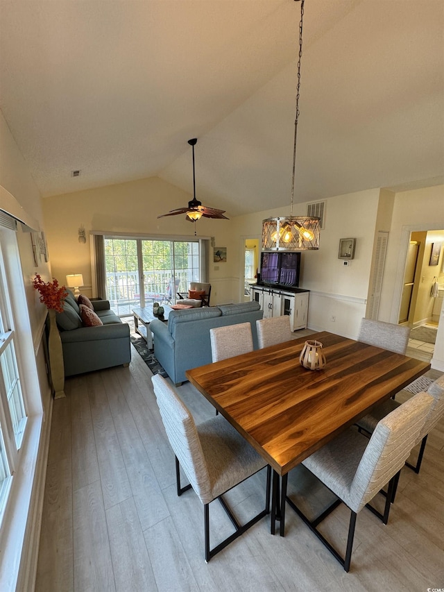 dining space featuring light wood-type flooring, visible vents, ceiling fan, and vaulted ceiling