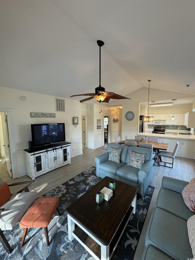 living room with visible vents, a ceiling fan, lofted ceiling, and wood finished floors