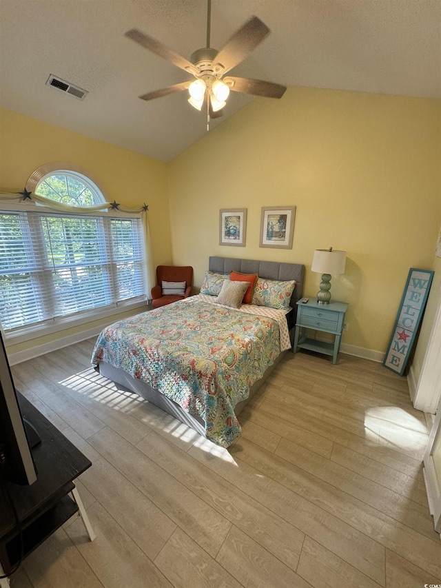 bedroom featuring visible vents, wood finished floors, baseboards, ceiling fan, and vaulted ceiling