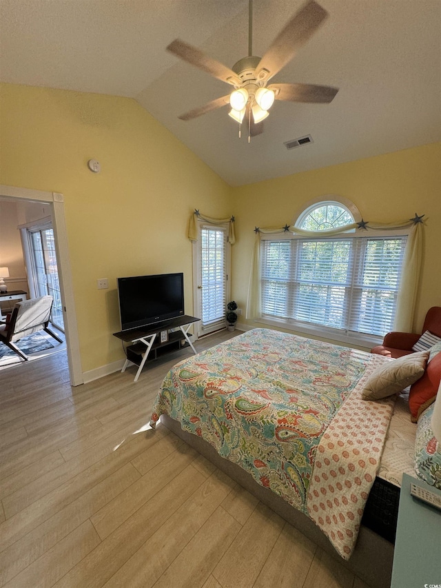 bedroom with visible vents, baseboards, lofted ceiling, wood finished floors, and a ceiling fan