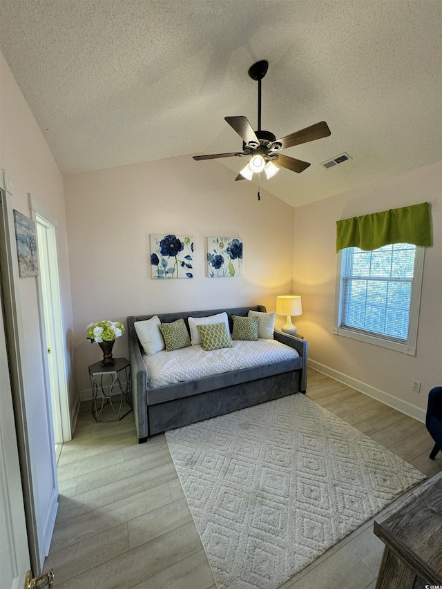 living area featuring lofted ceiling, a ceiling fan, visible vents, and light wood finished floors