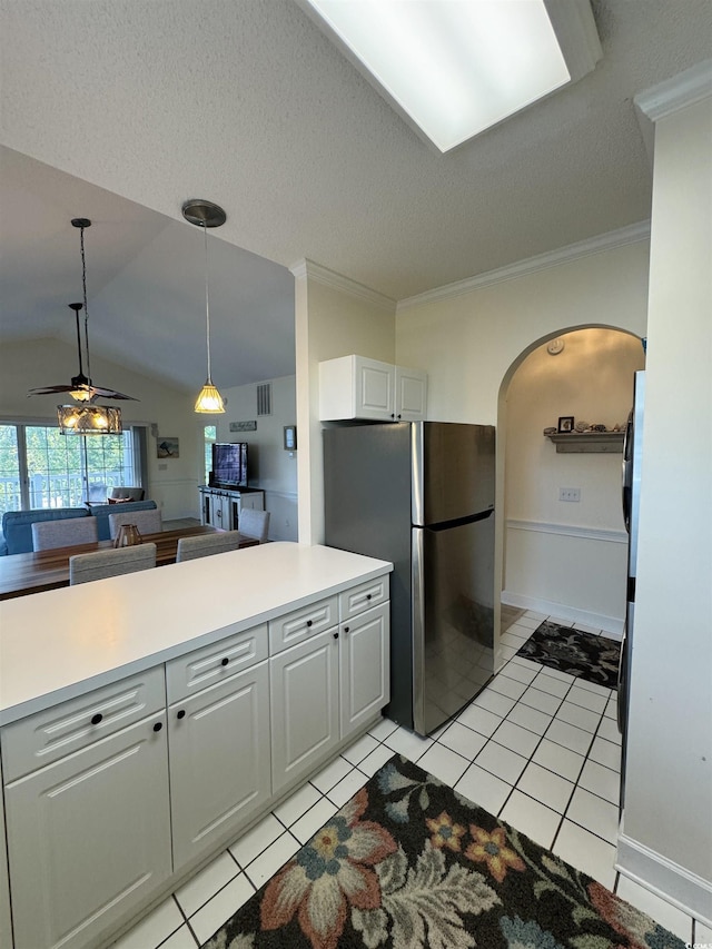 kitchen with light tile patterned floors, arched walkways, crown molding, and freestanding refrigerator