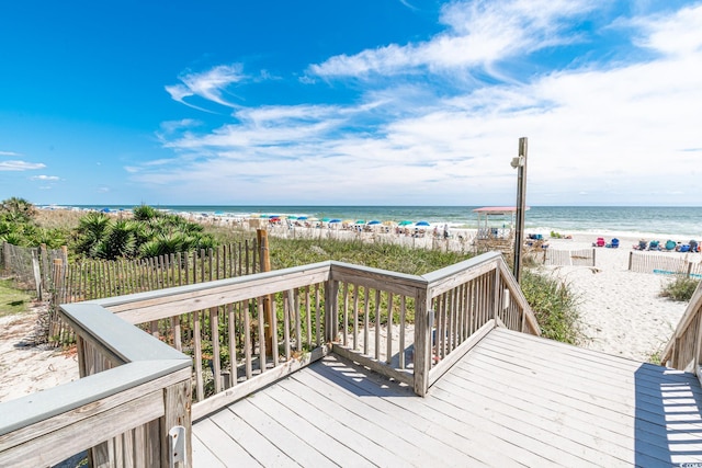 wooden terrace featuring a beach view and a water view