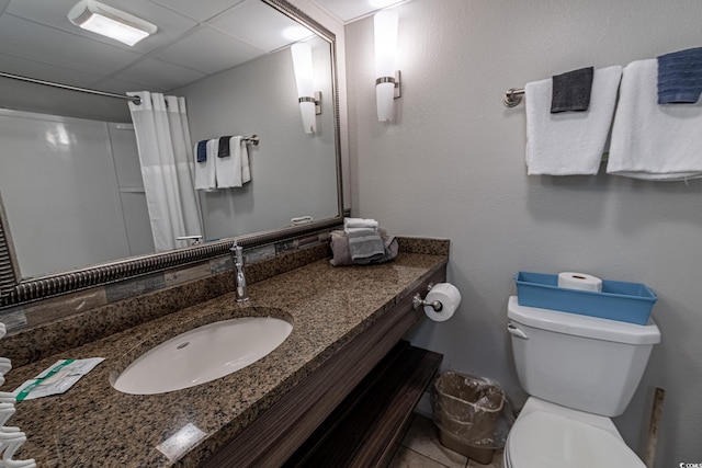 bathroom with curtained shower, a paneled ceiling, toilet, and vanity