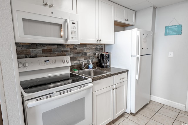 kitchen featuring white appliances, light tile patterned floors, a sink, decorative backsplash, and white cabinets