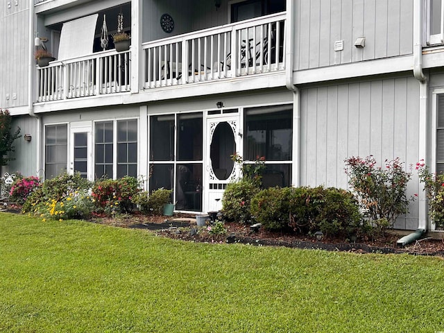 property entrance featuring a balcony and a yard