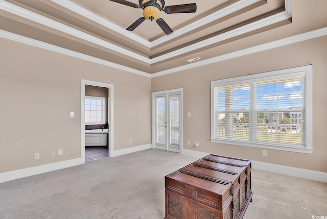 interior space with light colored carpet, ceiling fan, ornamental molding, and a raised ceiling