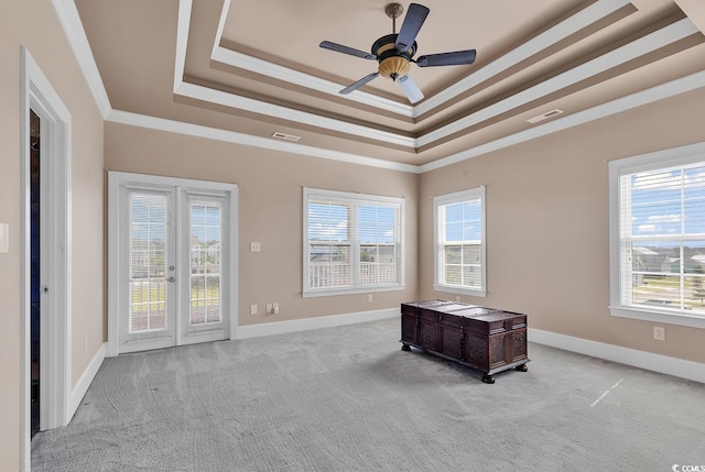 interior space with a tray ceiling, ornamental molding, light colored carpet, and ceiling fan