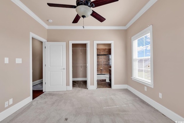 unfurnished bedroom featuring crown molding, ensuite bath, carpet floors, and ceiling fan