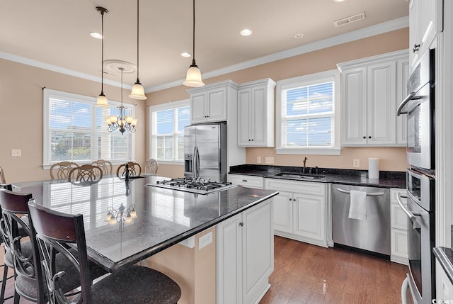 kitchen with a notable chandelier, wood-type flooring, crown molding, stainless steel appliances, and sink