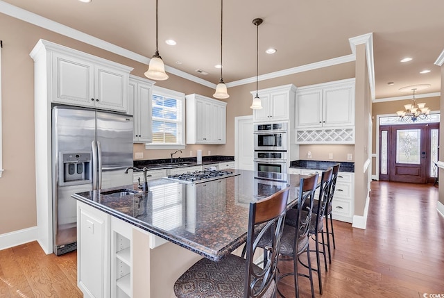 kitchen featuring hardwood / wood-style flooring, decorative light fixtures, stainless steel appliances, sink, and a spacious island