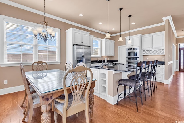 kitchen with white cabinets, an inviting chandelier, stainless steel appliances, light hardwood / wood-style floors, and pendant lighting