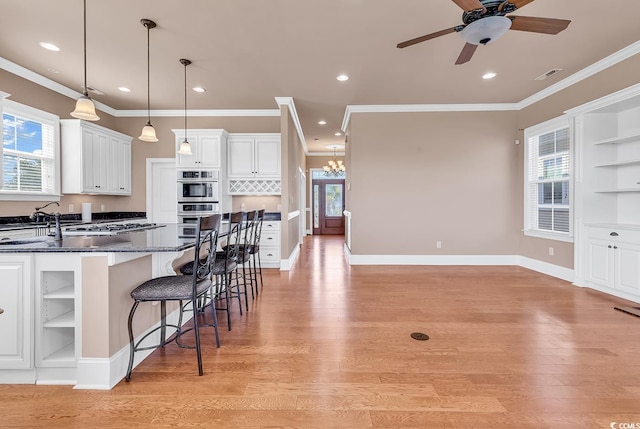 kitchen featuring ceiling fan with notable chandelier, plenty of natural light, and white cabinets