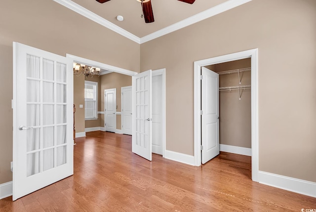 unfurnished bedroom featuring crown molding, light hardwood / wood-style flooring, ceiling fan with notable chandelier, and a closet