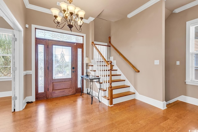 entryway featuring light wood-type flooring, crown molding, and an inviting chandelier