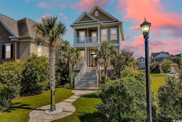 view of front of property featuring a balcony, a yard, and a porch