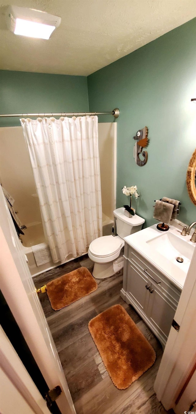 full bathroom featuring wood-type flooring, vanity, shower / bath combo with shower curtain, and toilet