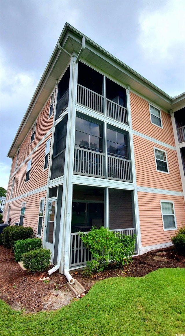 rear view of house with a balcony and a yard