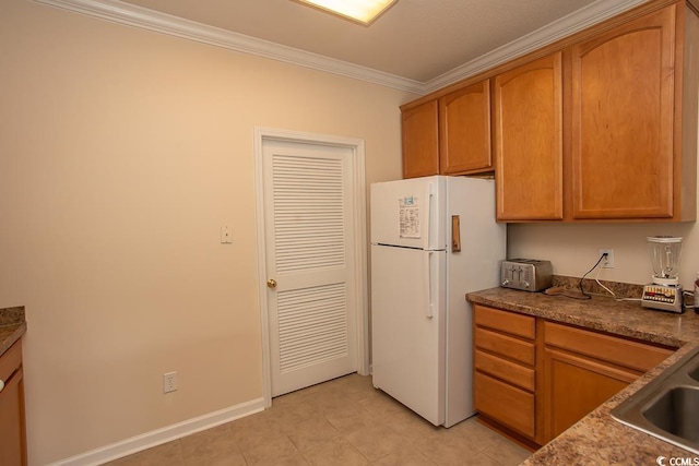 kitchen featuring white fridge, crown molding, and sink