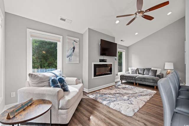 living room featuring a wealth of natural light, vaulted ceiling, dark hardwood / wood-style floors, and ceiling fan