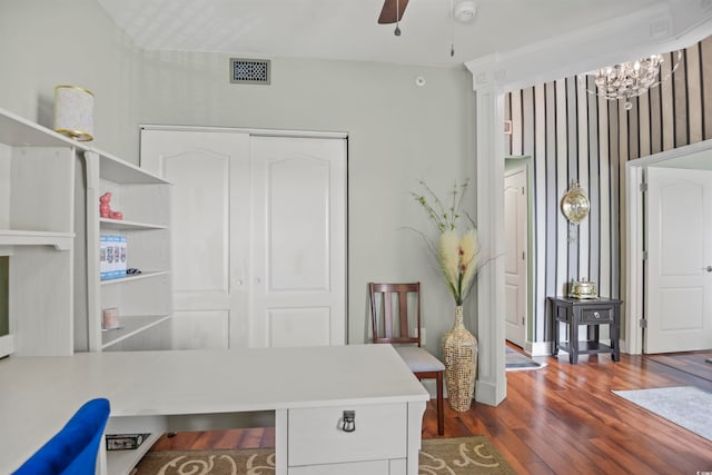 office with ceiling fan with notable chandelier and dark wood-type flooring