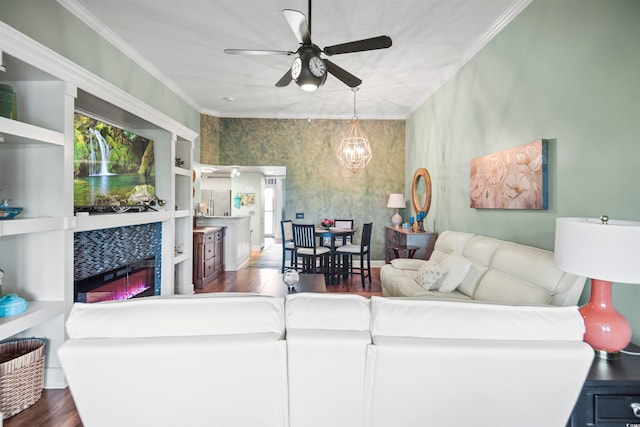 living room featuring ceiling fan with notable chandelier, built in shelves, crown molding, and dark hardwood / wood-style flooring