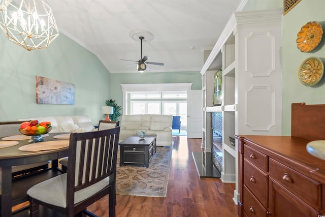 dining space with ornamental molding, vaulted ceiling, ceiling fan with notable chandelier, and dark hardwood / wood-style flooring