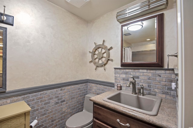 bathroom featuring tile walls, vanity, and toilet