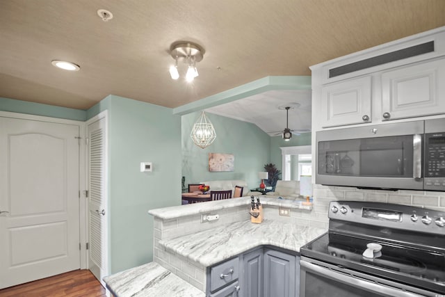 kitchen with kitchen peninsula, white cabinetry, dark wood-type flooring, and stainless steel appliances