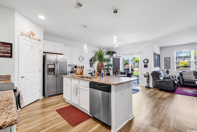 kitchen with white cabinetry, light stone countertops, appliances with stainless steel finishes, a center island with sink, and light hardwood / wood-style floors