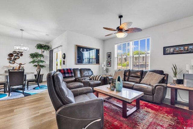 living room with ceiling fan with notable chandelier and light wood-type flooring