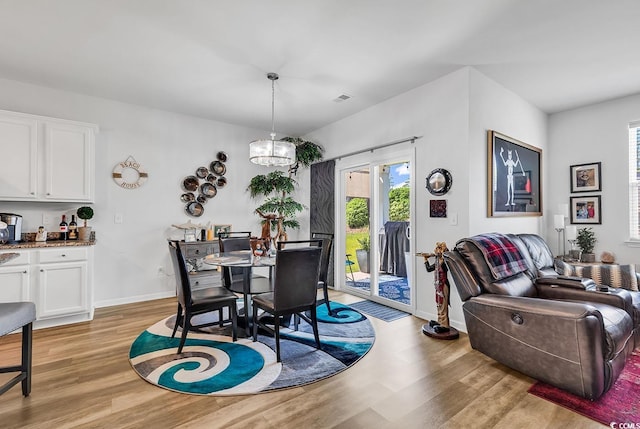 dining space with light hardwood / wood-style floors and a notable chandelier