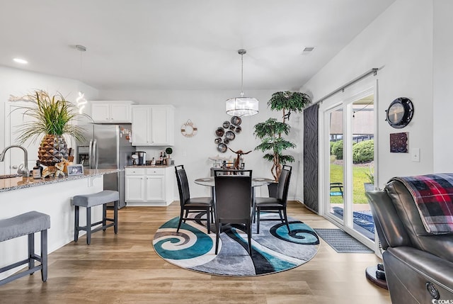 dining area featuring sink, an inviting chandelier, and light hardwood / wood-style flooring