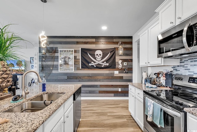 kitchen with light stone countertops, appliances with stainless steel finishes, hanging light fixtures, sink, and white cabinets