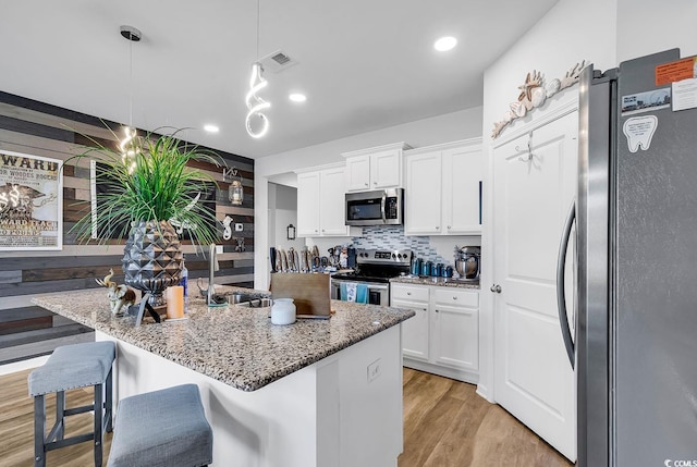 kitchen with light wood-type flooring, white cabinetry, stainless steel appliances, and a breakfast bar