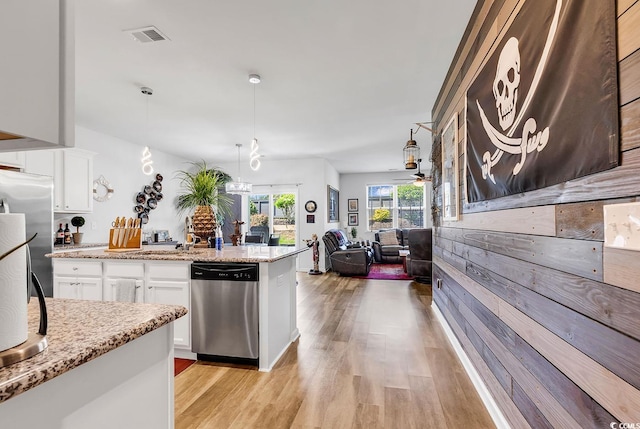 kitchen featuring light stone countertops, light hardwood / wood-style flooring, stainless steel dishwasher, hanging light fixtures, and white cabinets