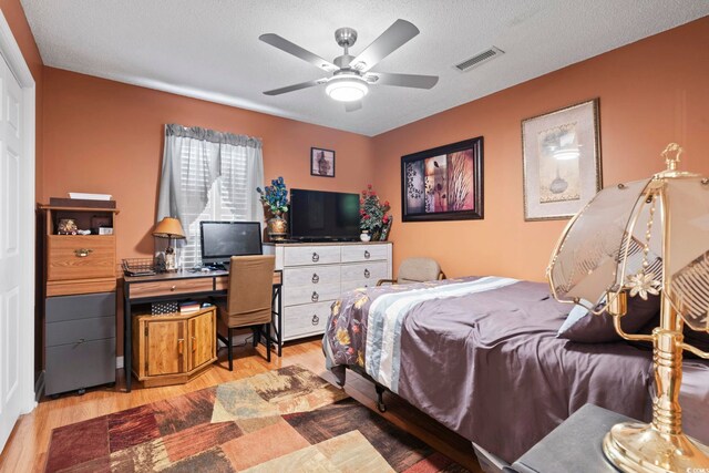 bedroom with hardwood / wood-style floors, ceiling fan, and a textured ceiling