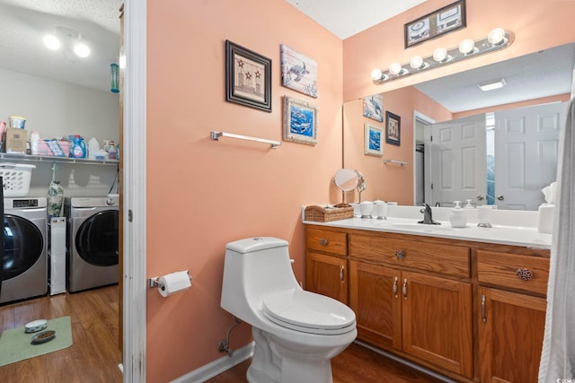 bathroom featuring separate washer and dryer, vanity, toilet, and hardwood / wood-style flooring