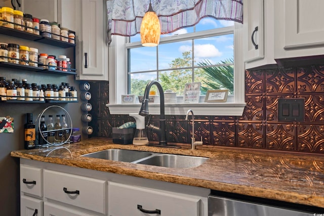 kitchen featuring stainless steel dishwasher, dark stone counters, sink, and white cabinets